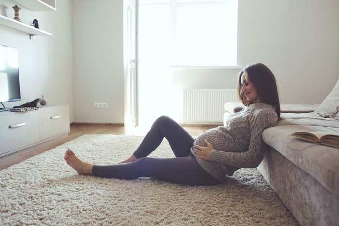 schwanger-veränderungen- 223004068 Sitzende Schwangere hält ihren Bauch