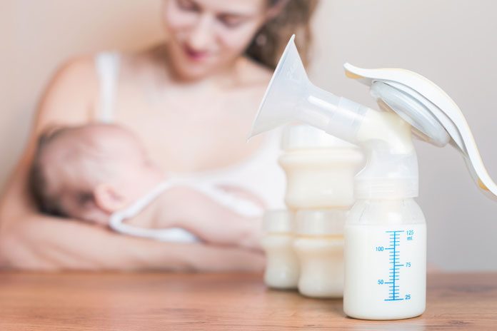 stillen-und-flasche-geben Mutter stillt, daneben stehen Fläschchen