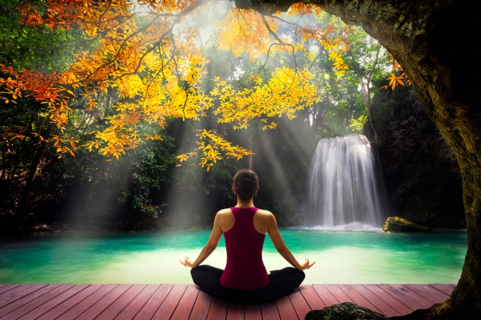 Frau-Yoga-bei-Wasserfall-288883520